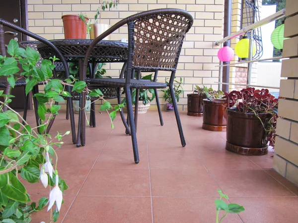 Photo of a chair, table and plants  on a terrace. ozy balcony