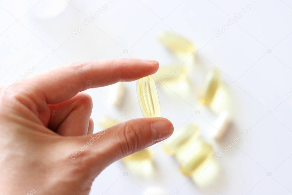 Womens hand is holding a pill. Tablets and pills laying on table. Background for pharmacology. Medicament composition.