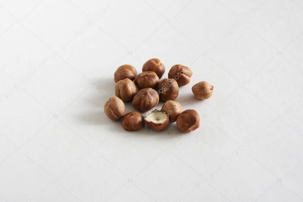 Hazelnuts in bowl on white background, top view with copyspace.  