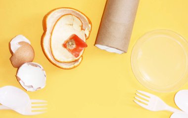 Çöp kutsaması. Sarı zemin üzerindeki çöp: cam, plastik, organik çöp, kağıt. 