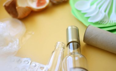 Çöp kutsaması. Sarı arkaplanda farklı çöp: cam, plastik, organik çöp, kağıt. 