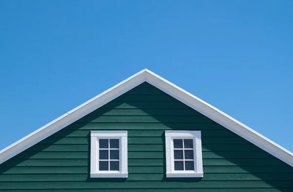 Groen huis en witte dak met blauwe hemel in zonnige dag — Stockfoto