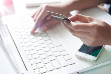 Kredi kartı tutan ve dizüstü bilgisayar kullanan eller. İnternetten alışveriş 