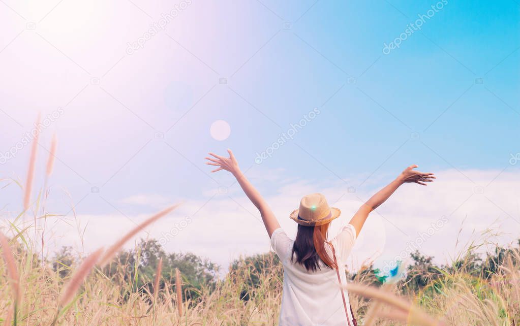 woman traveler with camera holding hat and breathing at field of grasses and forest, wanderlust travel concept, space for text, atmosperic epic moment 