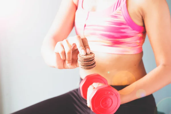 Fitness-Hündin in rosa Sport-BH mit roter Hantel und Snack in der anderen Hand mit Kopierraum — Stockfoto