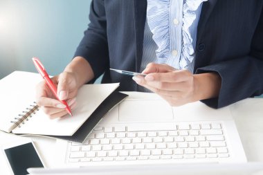 Dizüstü bilgisayar kullanan iş kadın koyu elbiseli kredi kartı, tutan bir