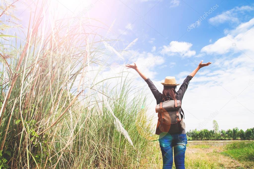woman traveler push hands and breathing at field of grasses and blue sky, wanderlust travel concept, space for text