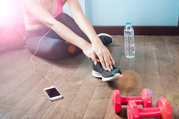 Fitness female in black pants and sneaker stretching after worko