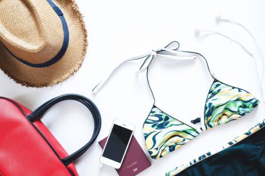 Düz yaz öğeleri kümesi yatıyordu. Bikini ile cep telefonu ve beyaz zemin üzerine yaz tatili için pasaport