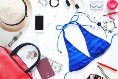 Düz beyaz arka plan üzerinde yaz tatili için in kız gerekli mavi bikini, cep telefonu, pasaport ve aksesuarları ile set koymak 