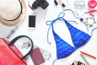 Düz beyaz arka plan üzerinde yaz tatili için in kız gerekli mavi bikini, cep telefonu, pasaport ve aksesuarları ile set koymak 