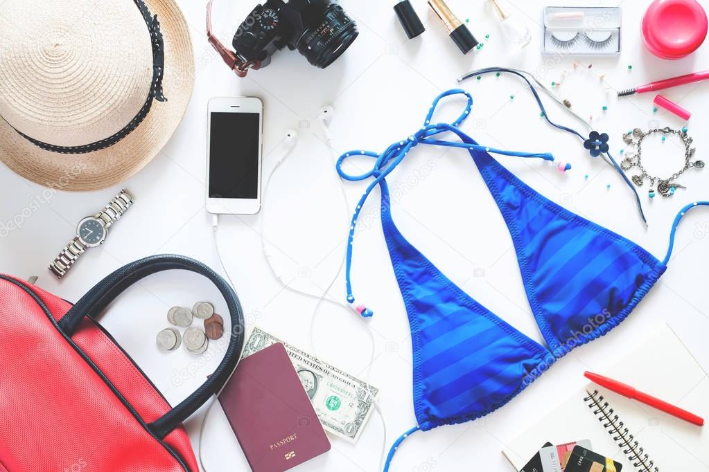 Flat lay set of girl essentials with blue bikini, mobile phone, passport and accessories for summer vacation on white background 