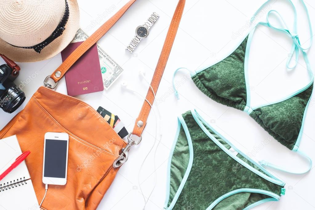 Set of summer holiday items. Green color bikini with mobile phone, leather bag, camera and passport for summer vacation on white background