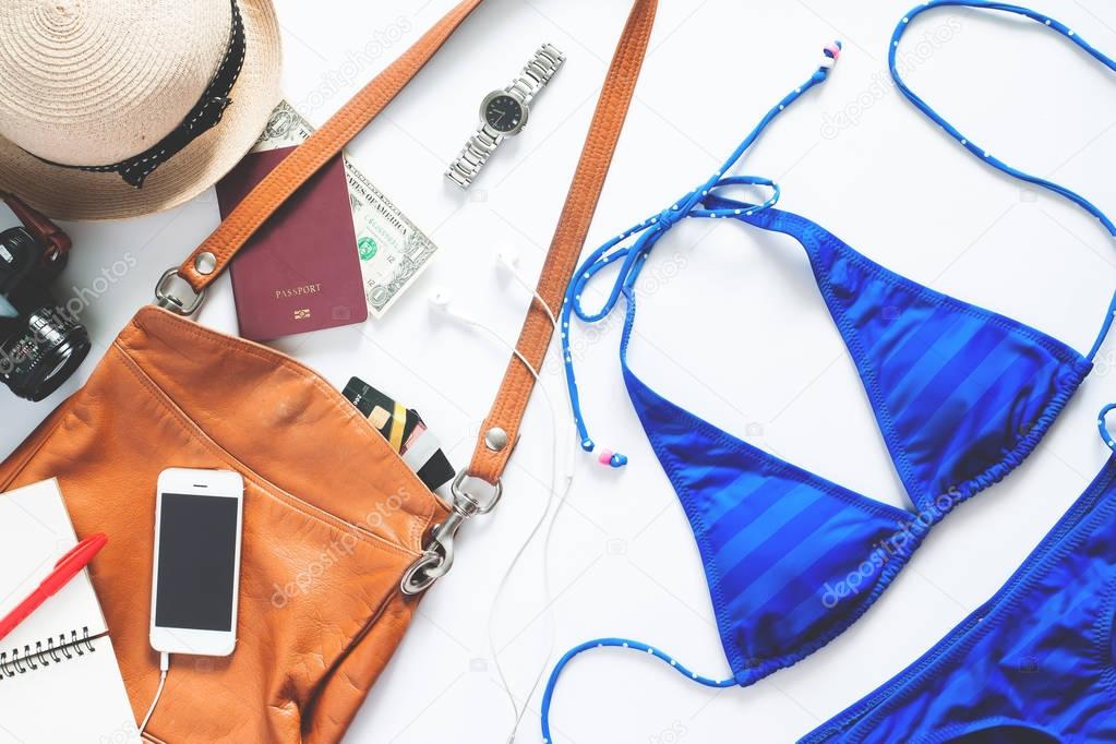 Set of summer items. Sexy blue stripe bikini with mobile phone, camera and passport for summer vacation on white background