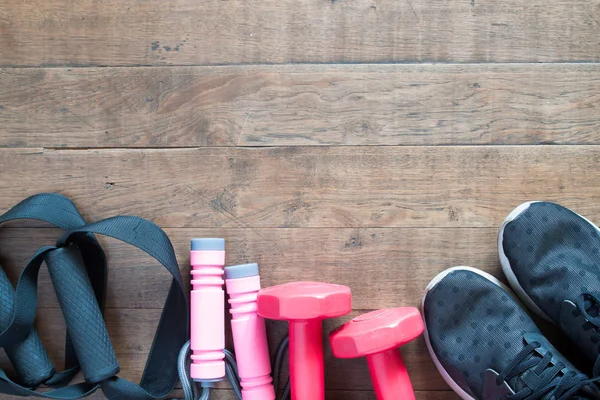 Flat lay of red dumbbells and sport equipment on wood background