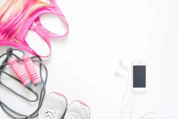 Ajuste plano de teléfono celular, sujetador deportivo rosa, cuerda de salto y zapatillas de deporte — Foto de Stock
