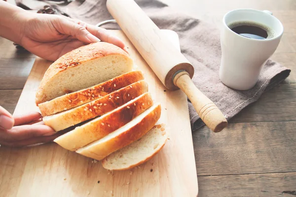 Mulher mão segurando pão em placa de madeira com ferramentas de cozinha e xícara de café — Fotografia de Stock