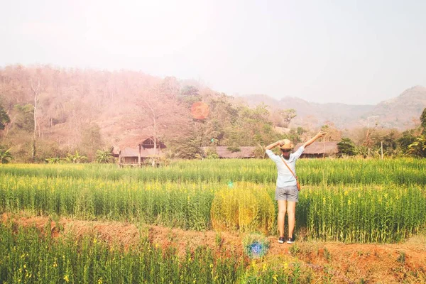 Chica feliz viajero de pie en el campo de las flores, vacaciones de verano — Foto de Stock
