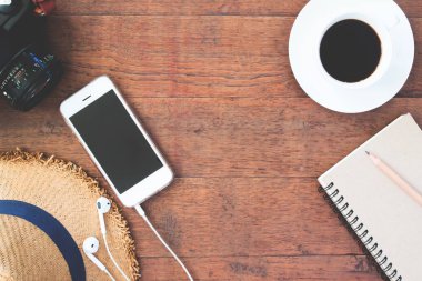Ahşap arka plan üzerinde fincan kahve kamera ve dizüstü bilgisayar ile smartphone ve genel gider görmek