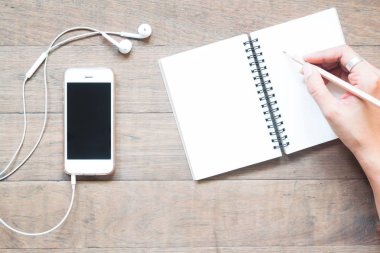 Smartphone ile boş defter ve kalem tutan kadın havai görünümü