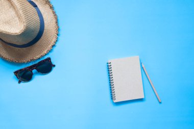 Düz defter kalem, şapka ve güneş gözlüğü üzerinde mavi col yatırın