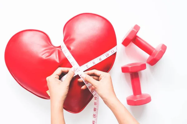 Woman hand holing measuring-tape on heart and dumbbell on white background, Healthy diet concept — Stock Photo, Image