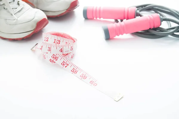 Measuring tape, sport shoes and jump rope in pink color on white — Stock Photo, Image