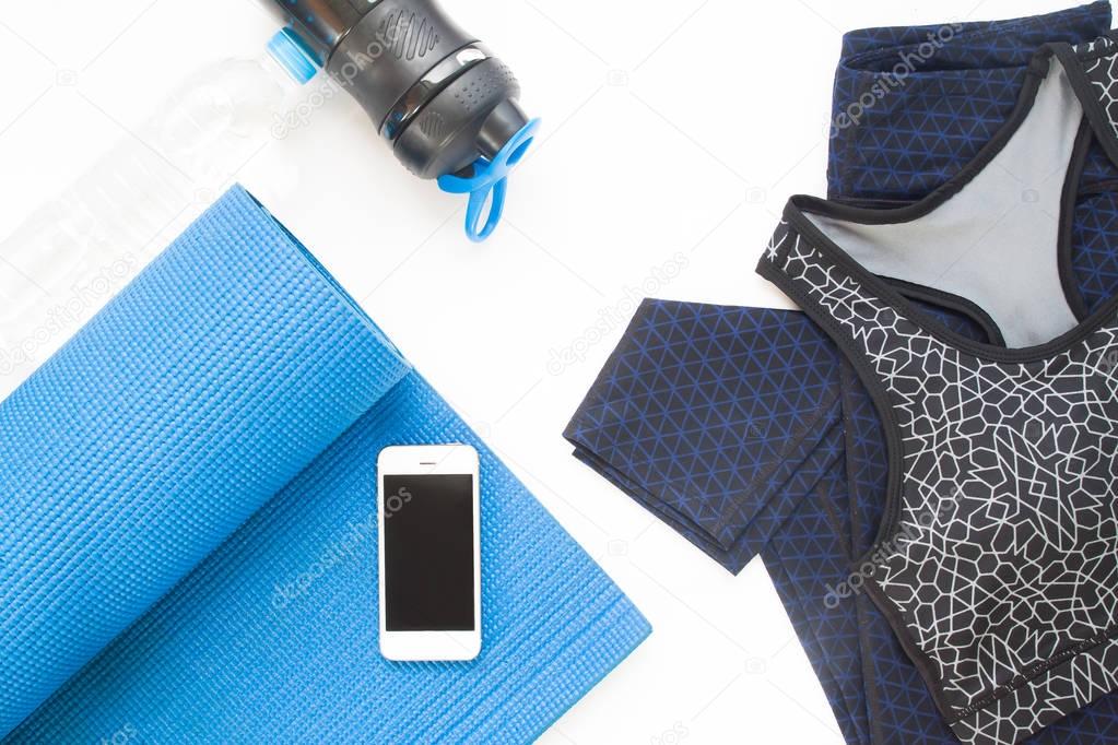 Overhead view of mobile device, yoga mat, yoga clothing and bott
