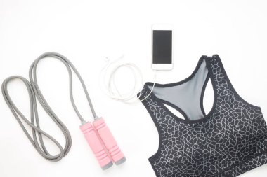 Düz smartphone, spor sutyen ve spor aletleri beyaz üzerinde yatıyordu 