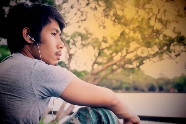 Aziatische gebroken hart man luisteren muziek, Vintage stijl kleur, donkere Toon — Stockfoto