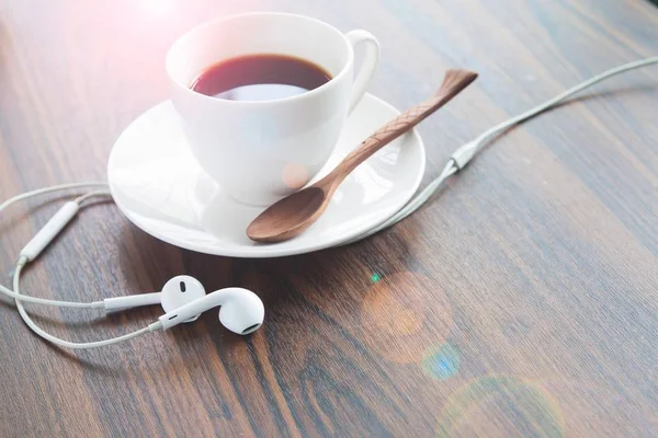 Fones de ouvido e xícara de café na mesa de madeira, conceito de estilo de vida — Fotografia de Stock