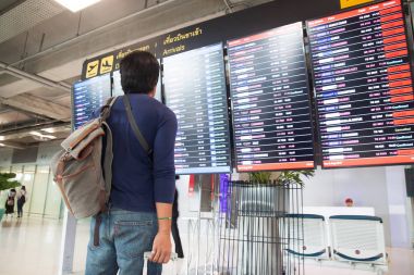 Bangkok, Tayland - 8 Ağustos 2017: Asya seyahat adam sırt çantası ve Bagaj bavul Suvarnabhumi Havaalanı uçuş programı bakarak devam. Suvarnabhumi Havaalanı Bangkok hizmet veren iki Uluslararası Havaalanı biridir.