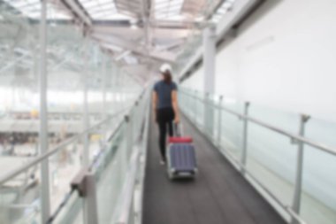 Bangkok, Tayland - 8 Ağustos 2017: Bulanık arka plan bavul yürüyüş geçitten Suvarnabhumi Airport adlı sürükleyerek Asyalı kadın. En popüler Se Asya Havacılık hub.