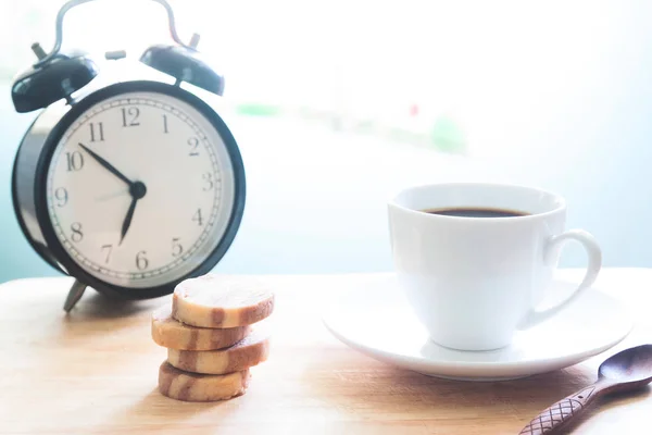 Inicie o conceito com xícara de café, biscoitos e despertador na mesa de madeira — Fotografia de Stock