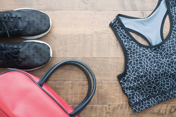 En iyi spor kadın öğelerin görünümünü ahşap arka plan, spor ayakkabı, spor sutyen ve çanta