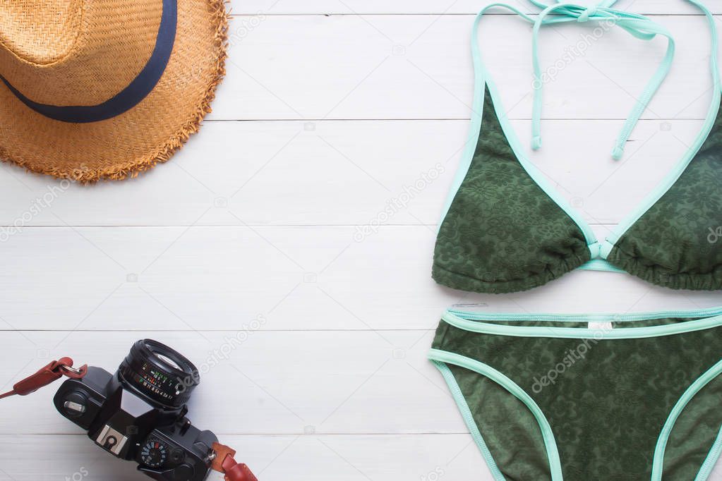 Summer vacation concept with green color bikini, straw hat and camera, Top view travel concept
