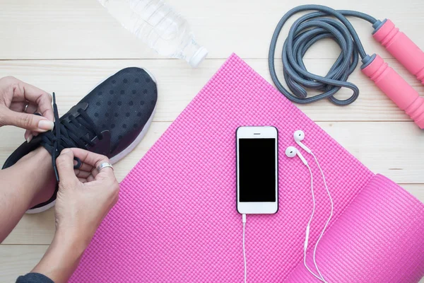 Draufsicht auf gesundes Lifestylekonzept, Frau bindet Schuhe mit Smartphone auf Yogamatte — Stockfoto