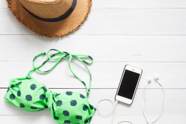 Bikini, hasır şapka ve Beyaz ahşap zemin, üstten görünüm üzerinde akıllı telefon