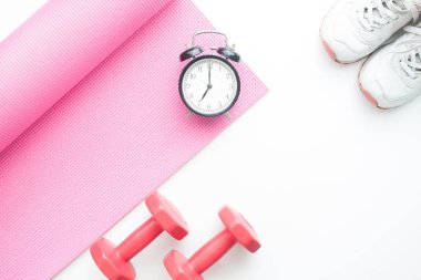 Yaratıcı düz sağlıklı ve diyet kavramının, çalar saat pembe yoga mat, halter ve spor ayakkabı beyaz zemin üzerinde yatıyordu