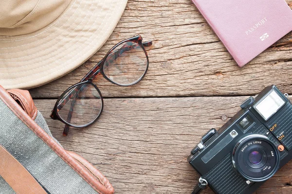 Creative flat lay of eyeglasses, hat, bag, camera and passport on wooden texture background, Travel vacation concept