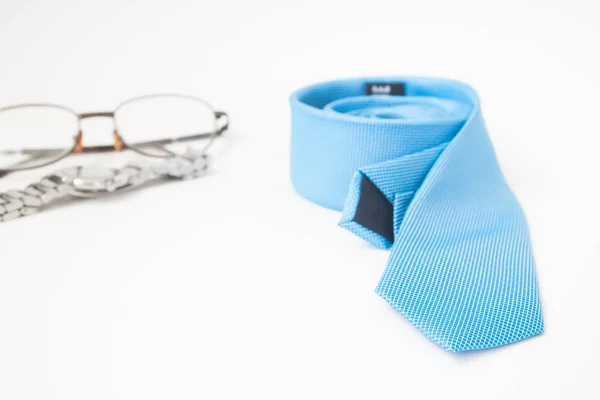 Gafas de vista, corbata y reloj de color azul sobre fondo blanco, complementos hombre — Foto de Stock