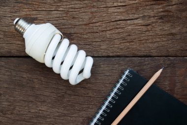 Ampul ve rustik ahşap arka plan üstünde defter