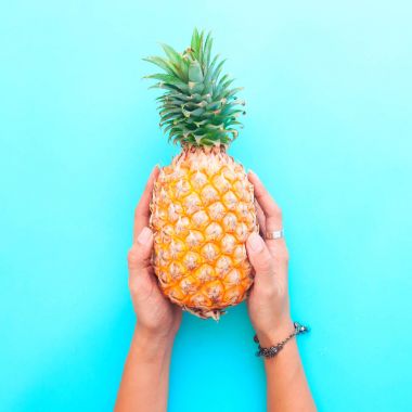 Ananas mavi renk arka planda, yaz tatil kavramı holding kadının eller