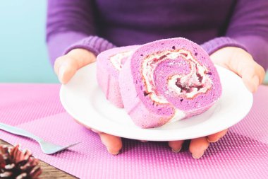 Yaban mersini saçtan tutarak kadının el rulo pasta, mor renk tonu kavramı, yaşam tarzı