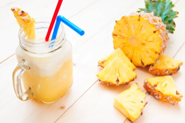 Fresh pineapple smoothie with pineapple slice on wooden table