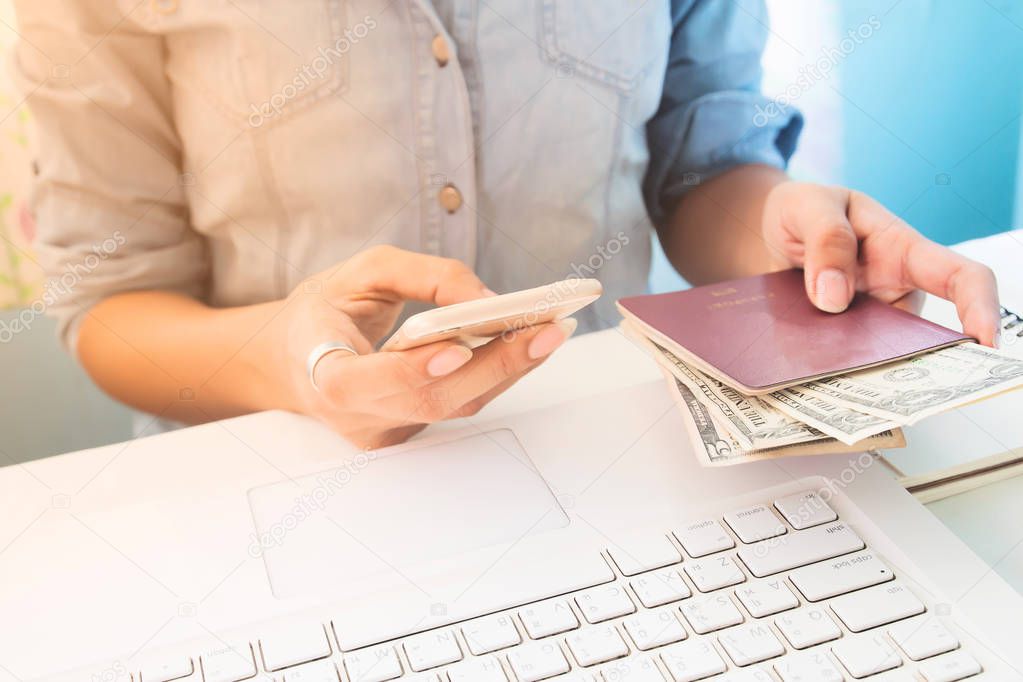 Woman wearing jeans shirt using mobile phone and holding passport with dollar bills on hand, Business and Finance, Travel lifestyle