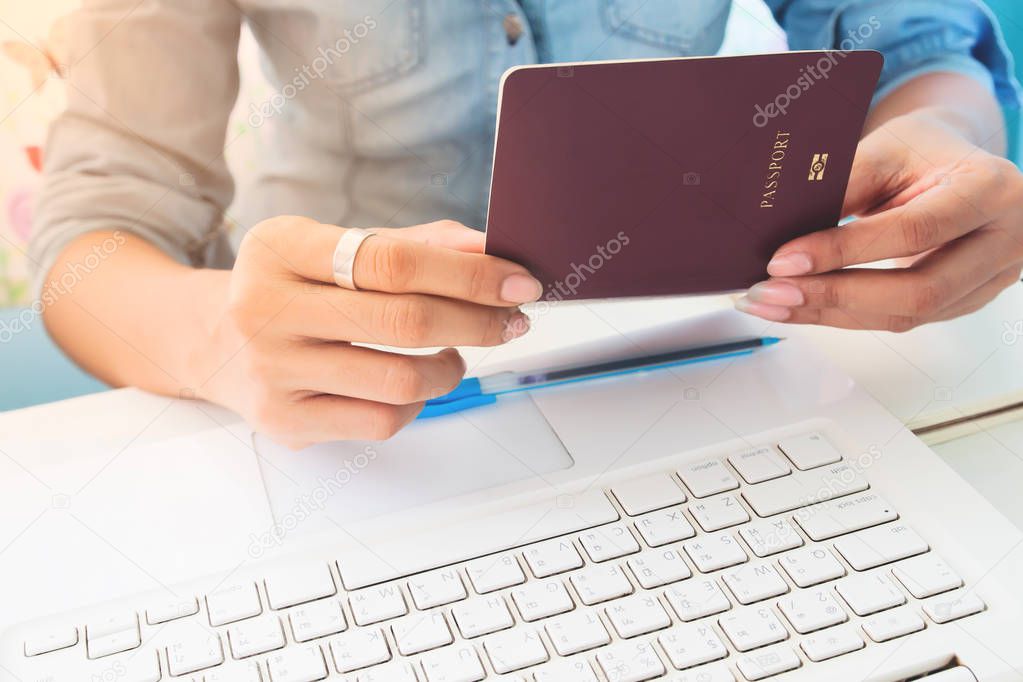 Close up image of woman's hands holding passport book on work space desk