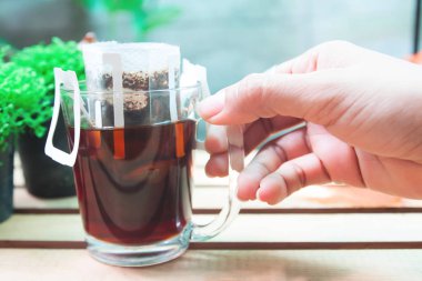 Kadın eli ile bir bardak kahve, damla damla çanta taze kahve arka plan Bahçe Manzaralı kapatın 