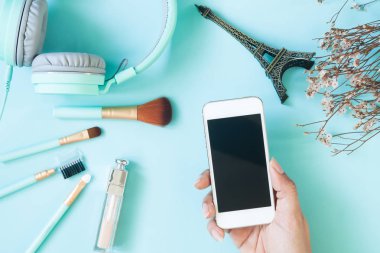 Kozmetik ve güzellik öğeleri, Pastel renk teması ile akıllı telefon tutan kadın el ile güzellik havai görünümü vurdu