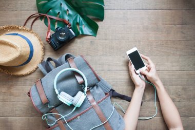 Kadının el smartphone, sırt çantası, kulaklık, ahşap masa, kamera kullanarak seyahat tatil